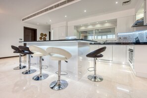 A modern kitchen with a central island, bar stools, and a large window.