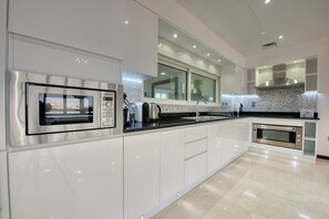 A modern kitchen with stainless steel appliances, a large window, and a tiled backsplash.