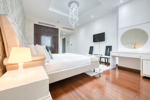Een moderne slaapkamer met een groot bed, nachtkastje en een bureau met stoel.