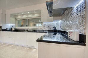 Una cucina moderna con mobili bianchi, un piano di lavoro nero e un backsplash con motivo geometrico.