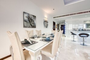 A modern dining area with a glass table, beige upholstered chairs, and contemporary artwork on the walls.