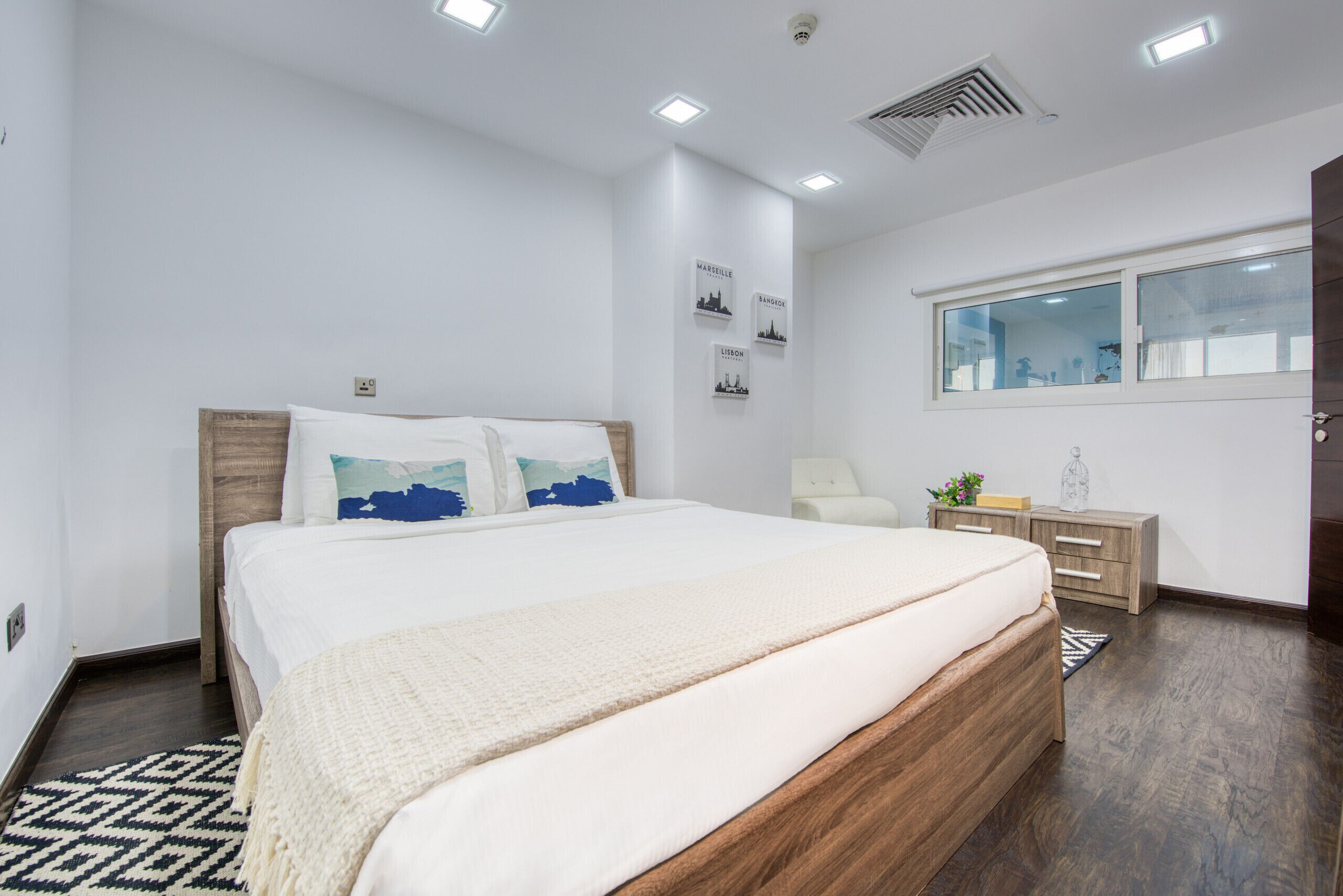 Ein Schlafzimmer mit einem hölzernen Bett, weißen Wänden, einem Fenster und einem Nachttisch.