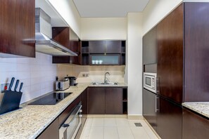 A modern kitchen with dark wooden cabinets, a stainless steel range hood, a microwave, and a toaster.