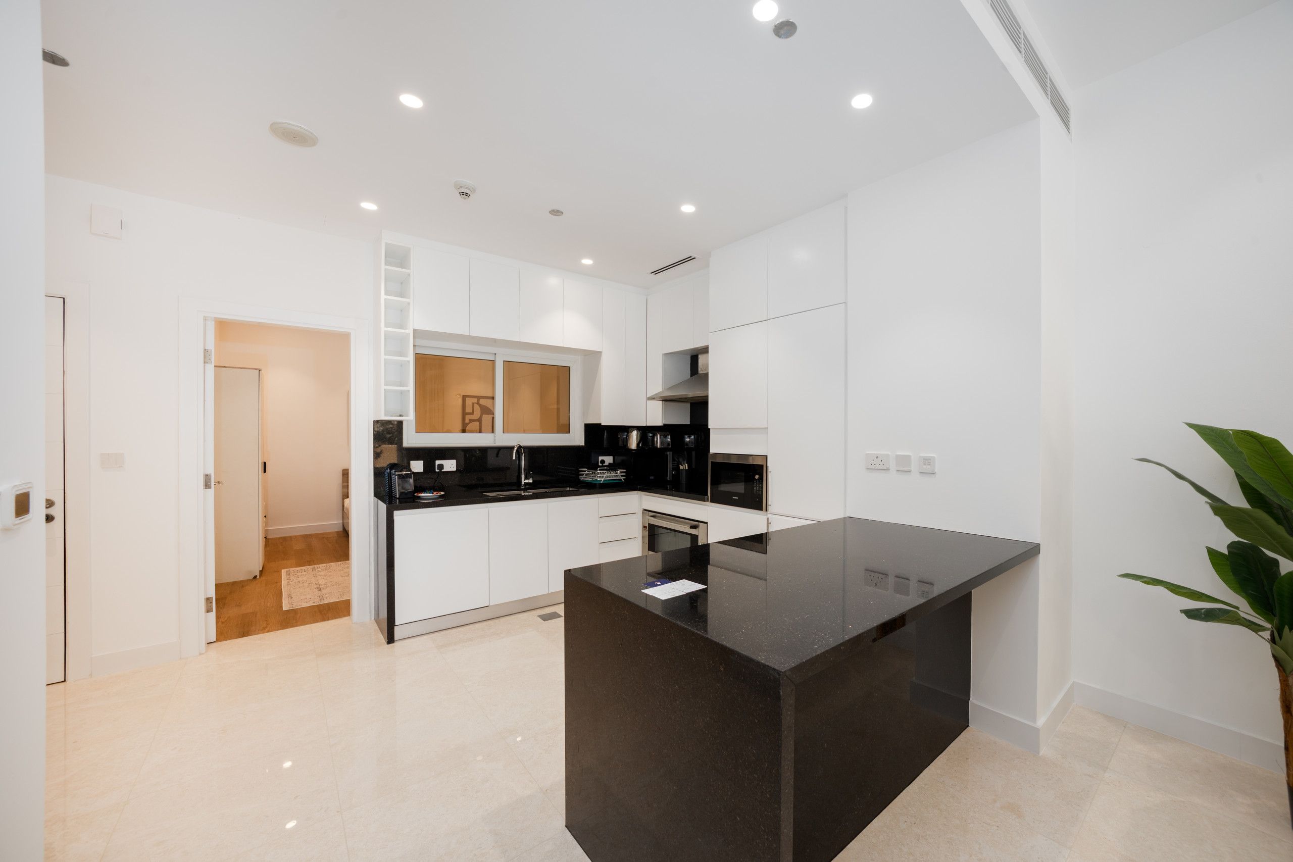 Een moderne keuken met witte kasten, een zwart aanrecht en een centraal eiland.