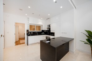 A modern kitchen with white cabinetry, a black countertop, and a central island.