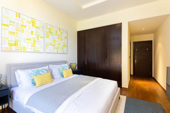 A modern bedroom with a large bed, a wardrobe, and abstract wall art.
