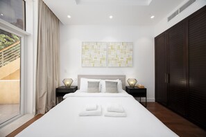 Ein modernes Schlafzimmer mit einem großen Bett, zwei Nachttischen, einem Kleiderschrank und einem Fenster mit Vorhängen.