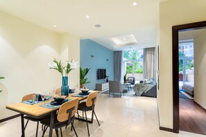 A modern dining area with a wooden table, chairs, and a vase of white flowers.