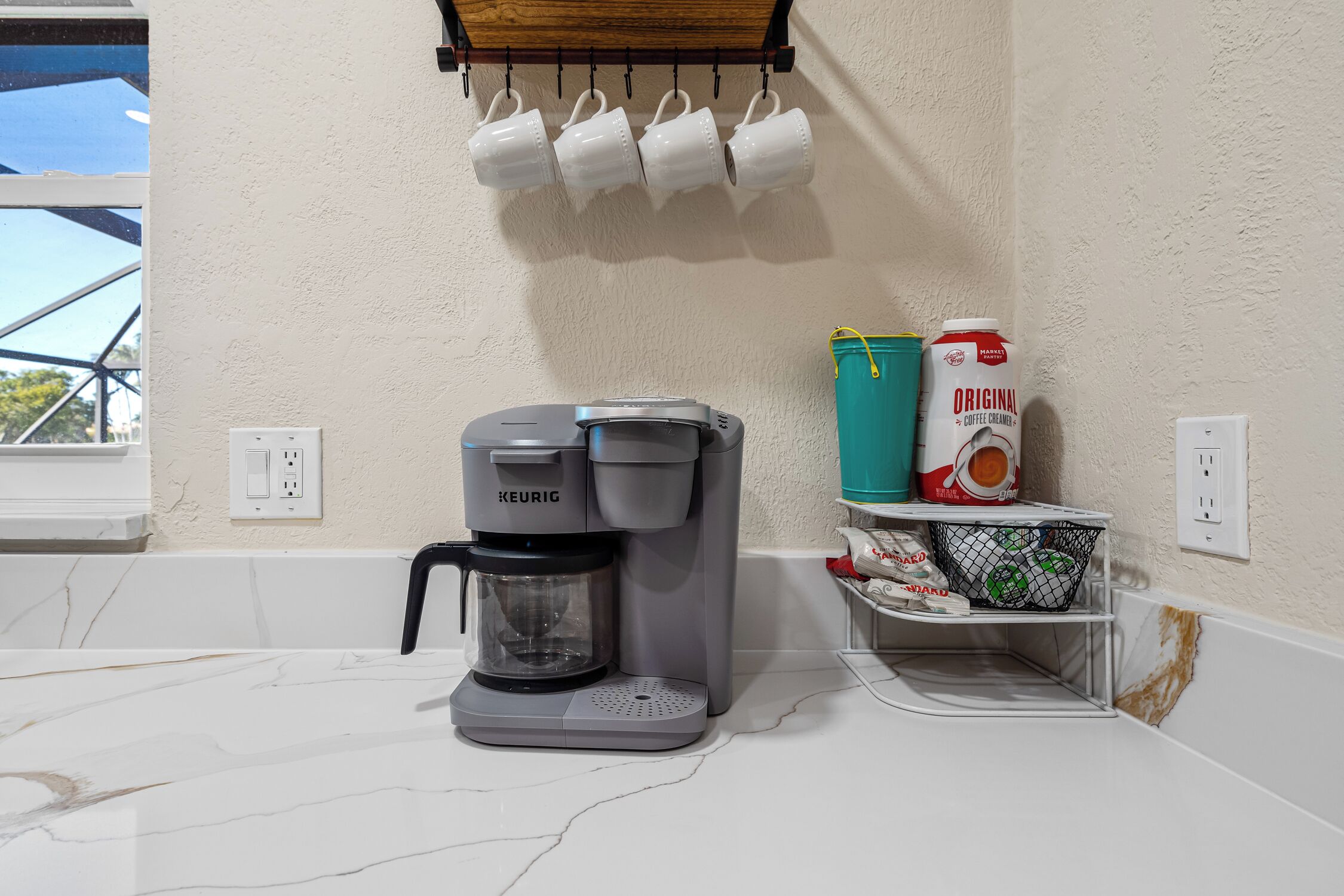 A kitchen with a Keurig coffee maker, a coffee maker, a coffee container, and a coffee bag on the counter.
