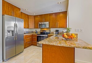 A modern kitchen with wooden cabinets, stainless steel appliances, and a granite countertop.