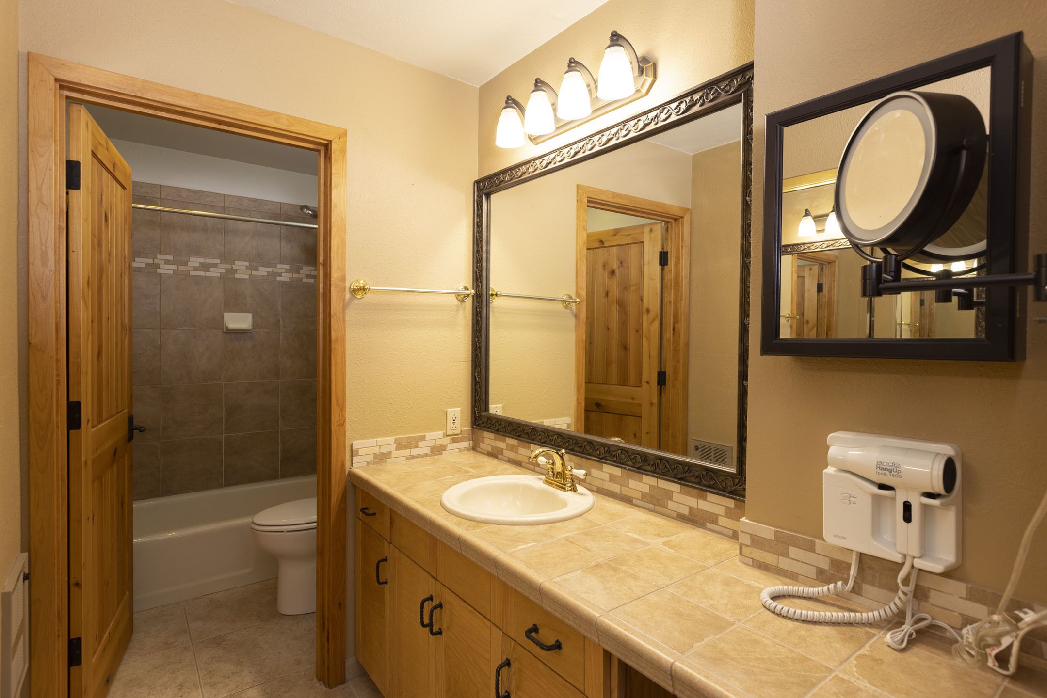 A bathroom with a sink, mirror, and a hairdryer on the wall.