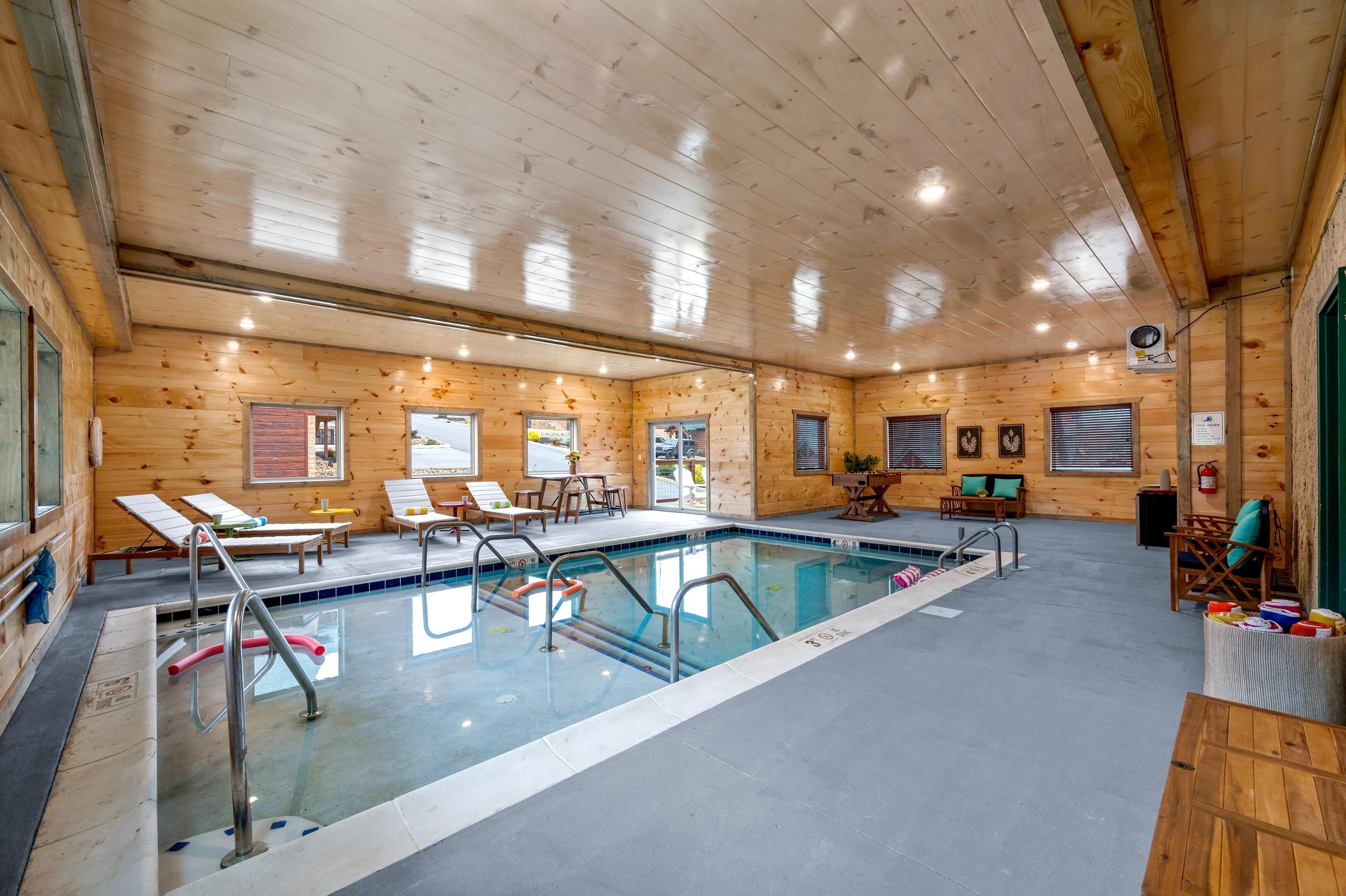 Ein Holzinnenraum mit Schwimmbad, Liegestühlen und einem Feuerlöscher.
