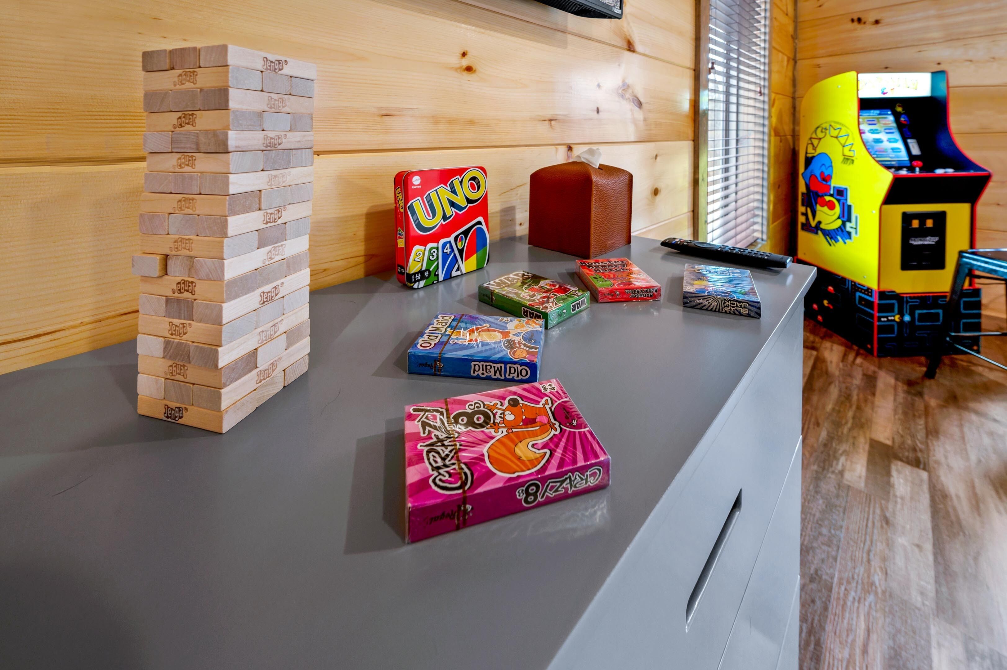Een houten wand met een stapel houten blokken, een rode doos en een geel automaatspel.