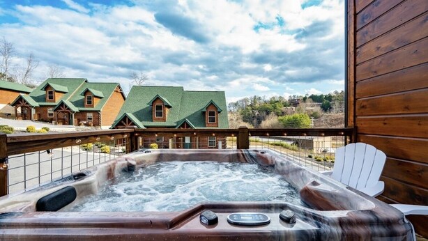 Un jacuzzi con barandillas de madera y vista a una hilera de cabañas al fondo.