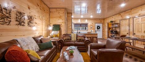 A cozy cabin interior with a wooden interior, leather furniture, a dining area, and a kitchen.