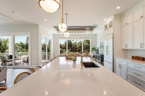 A spacious kitchen with a large island, white cabinetry, and pendant lighting.