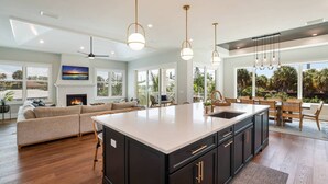 A spacious kitchen with a large island, black cabinetry, and pendant lighting. - Bikini Bottom: 5 Hole Mini Golft, Games,3 Blocks to Beach, Dog Friendly, Pool, by Anna Maria Life (Anna Maria)