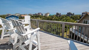 A wooden deck with white Adirondack chairs overlooking a residential area with houses and a clear blue sky. - Oceanside, Private Pool, Pickleball Court, Ocean Views (Salvo)