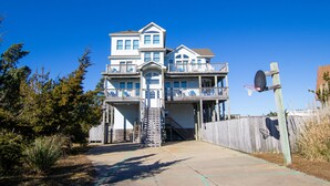A multi-story beachfront house with balconies, a basketball hoop, and a wooden fence. - Oceanside, Private Pool, Pickleball Court, Ocean Views (Salvo)