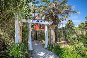 Ein begrenzter Zugang zu einer Privatstrandanlage namens Gulfplace, umgeben von üppiger Vegetation und Palmen.