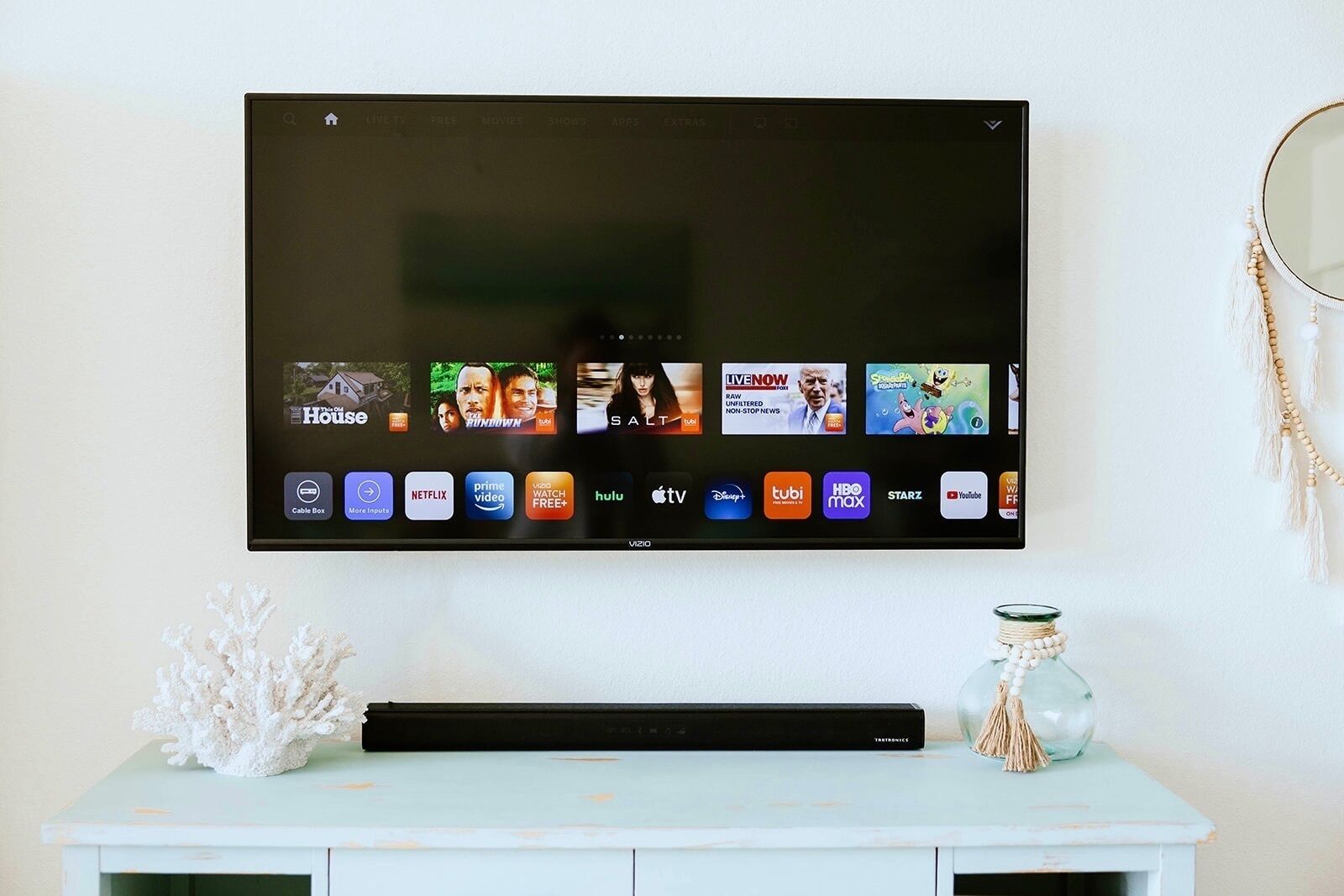 A flat-screen TV mounted on a wall displaying various streaming services.