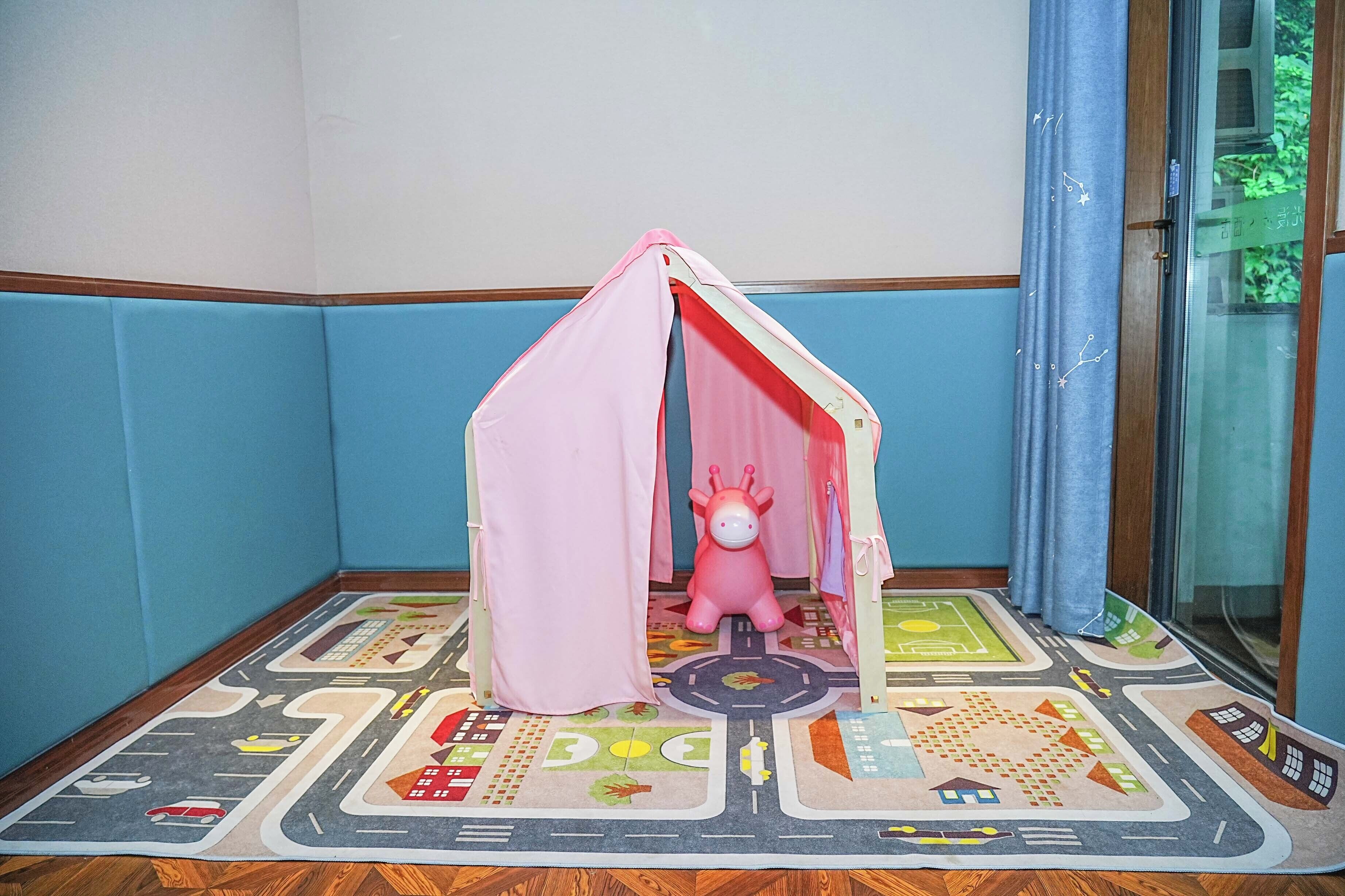 A corner room with a play tent and a toy horse.
