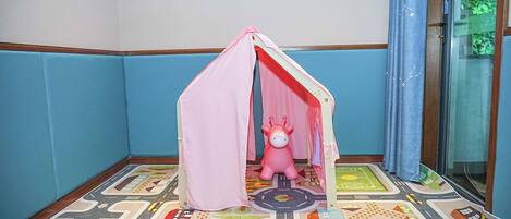 A corner room with a play tent and a toy horse.