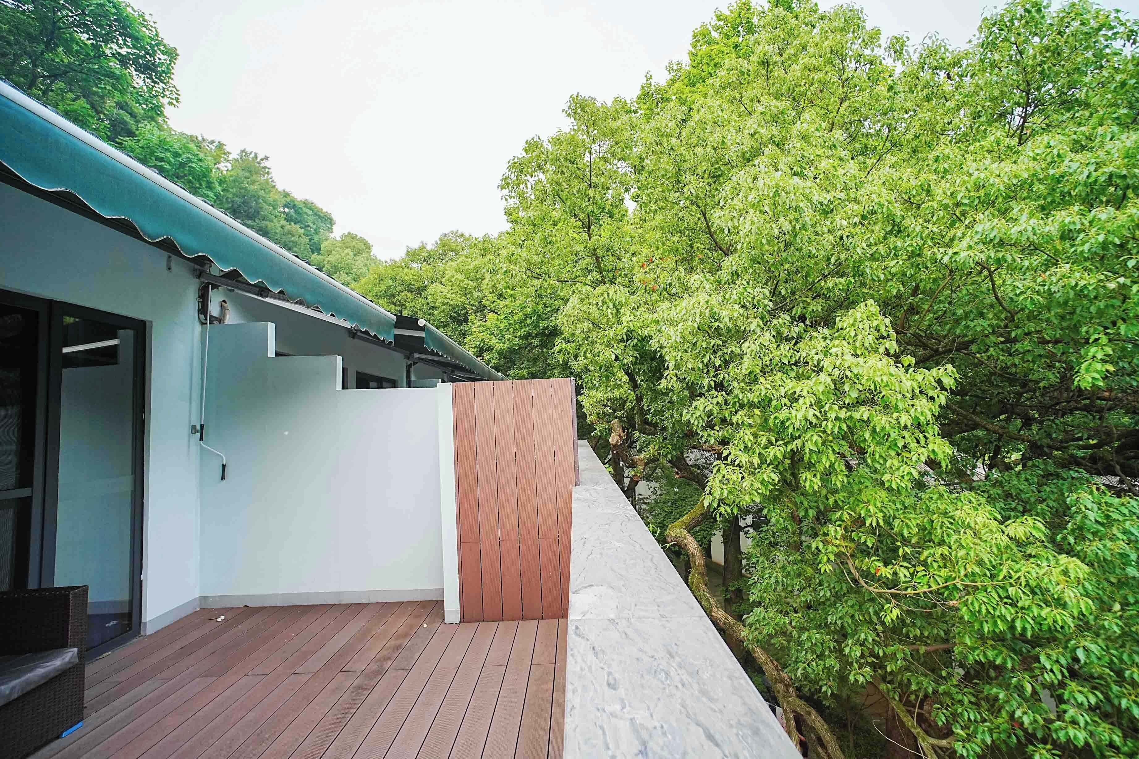 Un bâtiment moderne doté d’une terrasse en bois et offrant une vue sur une végétation luxuriante.