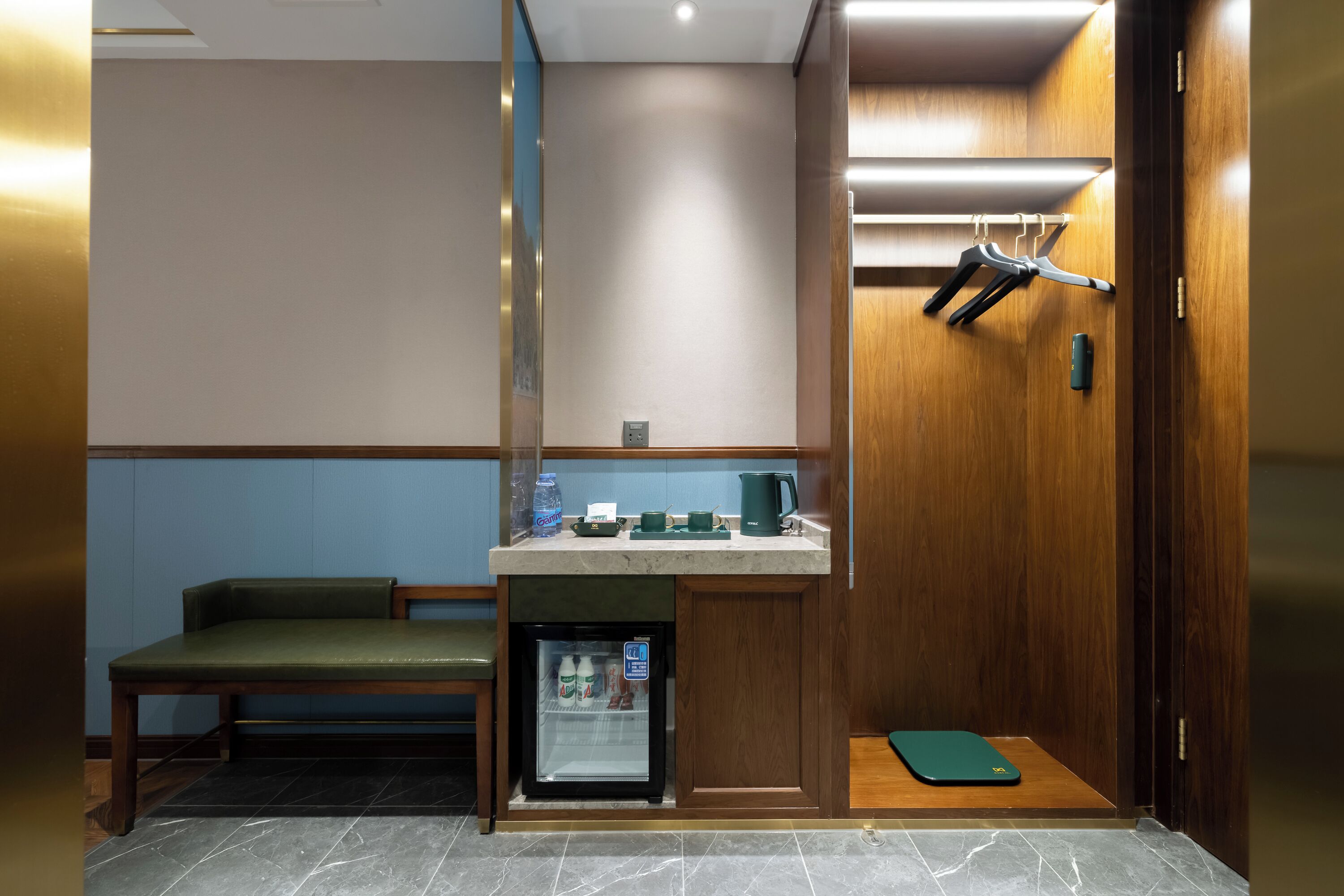 A compact hotel room with a kitchenette, a seating area, and a small refrigerator.