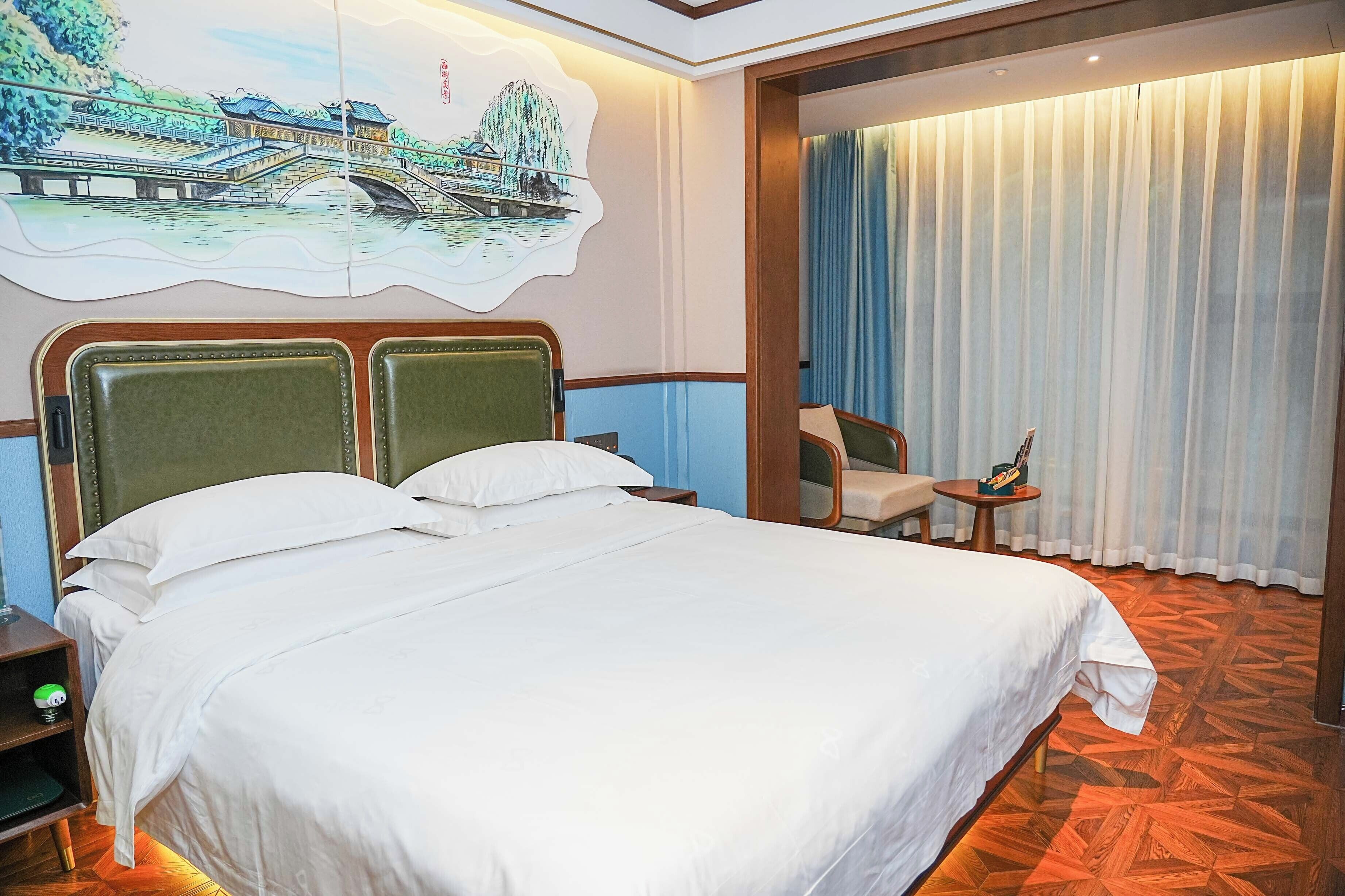 Una camera d'albergo con un letto grande, un comodino, una sedia, un tavolino e una tenda.