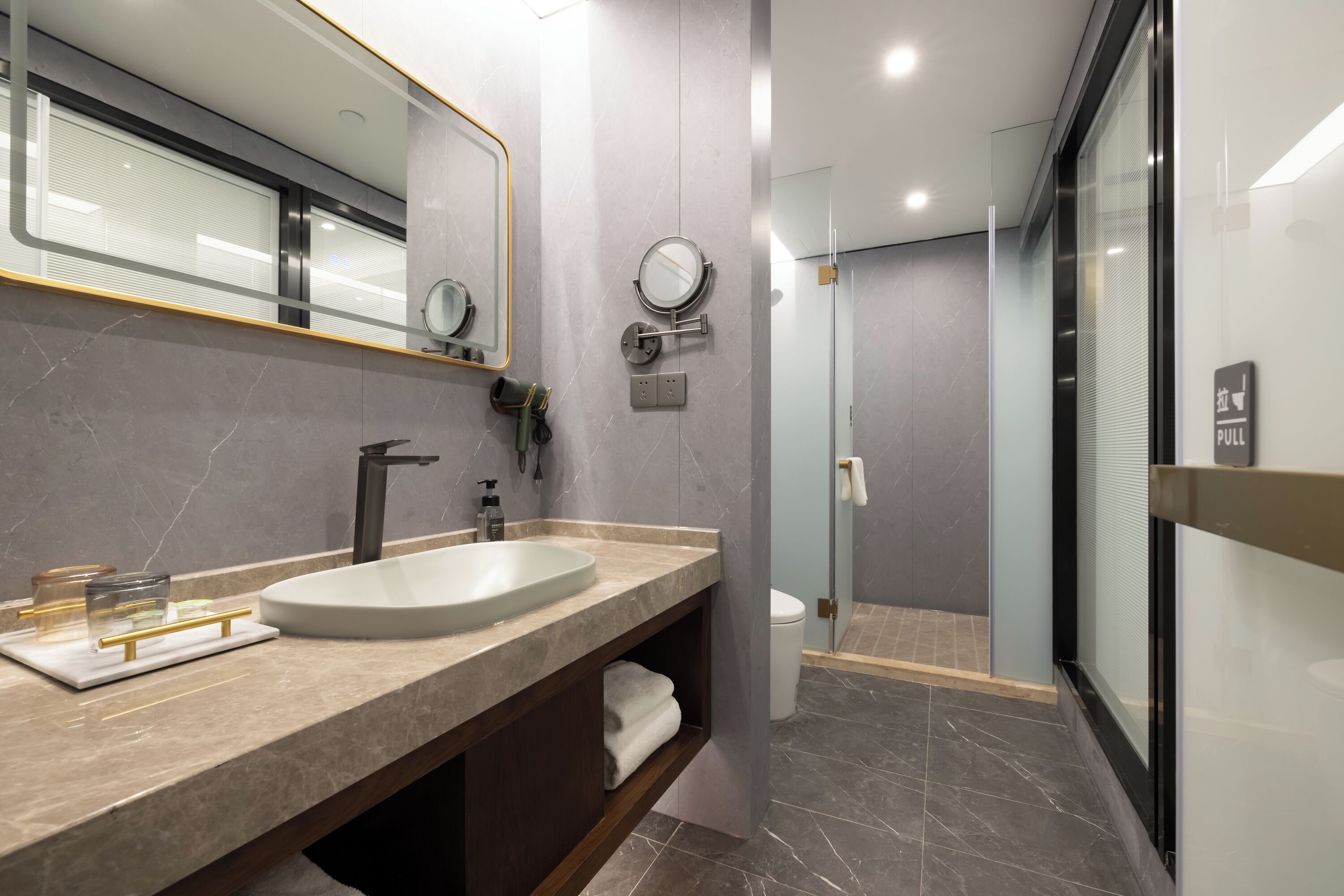A modern bathroom with a large sink, mirror, and a glass-enclosed shower.