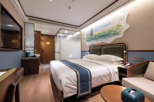 A hotel room with a large bed, a desk, a chair, a sofa, and a painting on the wall.
