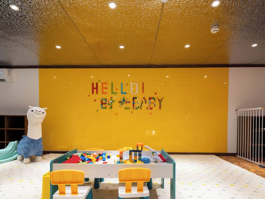 Une pièce bien éclairée avec un mur jaune, une table avec des jouets et un lama en peluche.