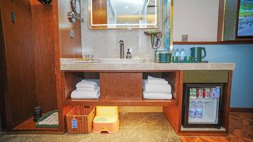 A bathroom with a double sink, a mirror, a towel rack, a small refrigerator, and a wooden vanity.