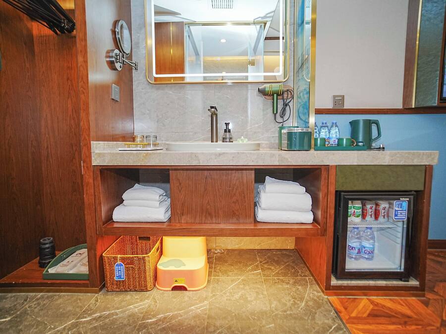 A bathroom with a double sink, a mirror, a towel rack, a small refrigerator, and a wooden vanity.