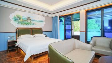 A hotel room with a bed, a chair, a desk with a computer, and a painting on the wall.