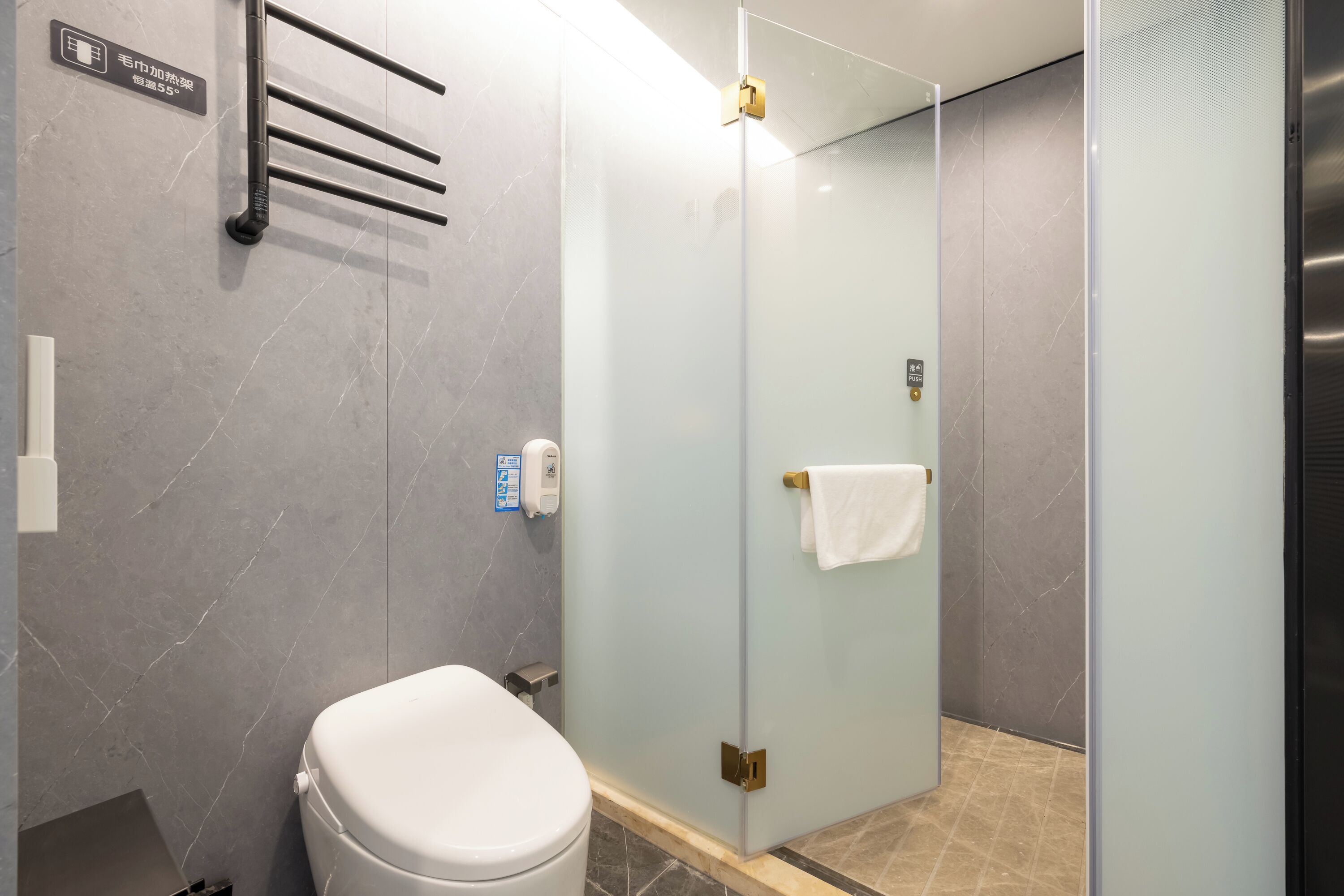 A modern bathroom with a toilet, a glass shower enclosure, and a towel rack.