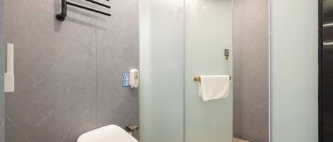 A modern bathroom with a toilet, a glass shower enclosure, and a towel rack.