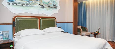 A hotel room with a bed, a chair, a small table, and a wall painting.