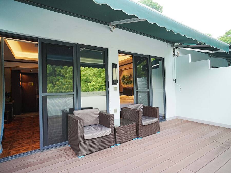 Un espacio exterior techado con mobiliario de mimbre y puertas correderas de vidrio que dan a un ambiente interior.