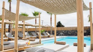 A poolside area with lounge chairs, umbrellas, and a clear blue pool. - Aqua Blu (Hersonissos)