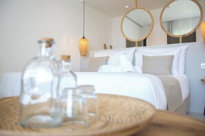 A hotel room with a neatly made bed, two round mirrors, and a wicker table with glass bottles. - Aqua Blu (Hersonissos)