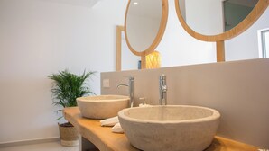 Une salle de bain moderne avec deux grands lavabos en pierre de forme ovale et un meuble-lavabo en bois.