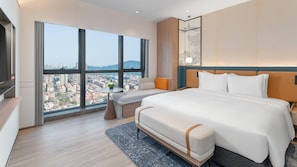 A modern hotel room with a large bed, a seating area, and a view of a cityscape. - Holiday Inn Express Shunde Daliang (Foshan)