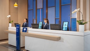 A hotel reception desk with three receptionists, a digital information kiosk, and a sign indicating 'Diamond Elite' membership. - Holiday Inn Express Shunde Daliang (Foshan)