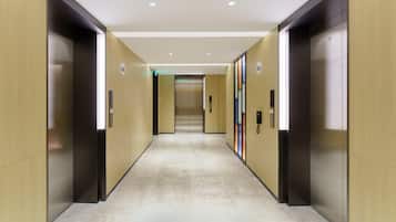 A modern hallway with elevators and a marble floor.