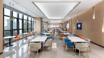 A spacious, modern dining area with high ceilings, large windows, and a variety of seating options.