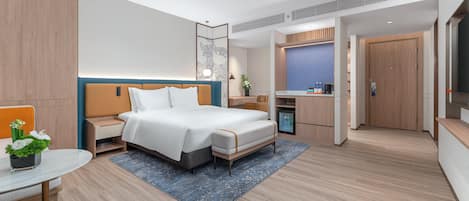 Quarto de hotel moderno com cama, mesa de cabeceira e área de trabalho com uma cadeira.