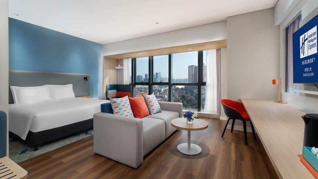 A modern hotel room with a bed, sofa, and a small table.