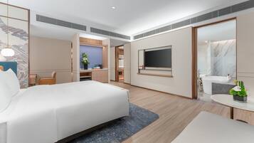 Una habitación de hotel moderna con una cama grande, un escritorio, un televisor y un baño con bañera y espejo.